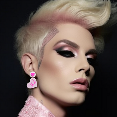 Portrait of a androgynous blonde hair person in their early 20's wearing soft glam pink makeup and dangle heart earrings that say 