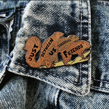 Pin with two squirrels and 'Just Us Squirrel Friends' text on a denim jacket.
